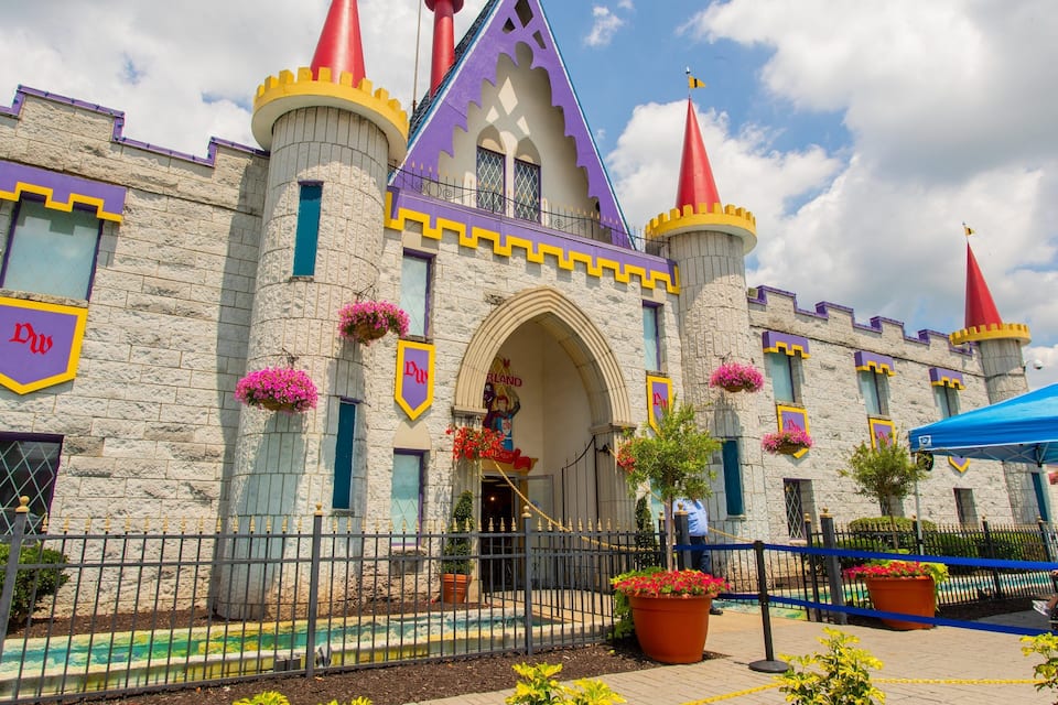 Un edificio con aspecto de castillo, con fachada morada y amarilla, un techo rojo a dos aguas y un letrero con el logotipo 'DW'.