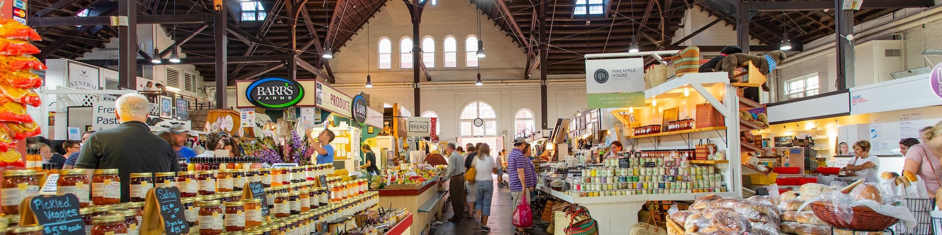 An indoor market with various stalls selling food items like bread, pastries, and condiments.