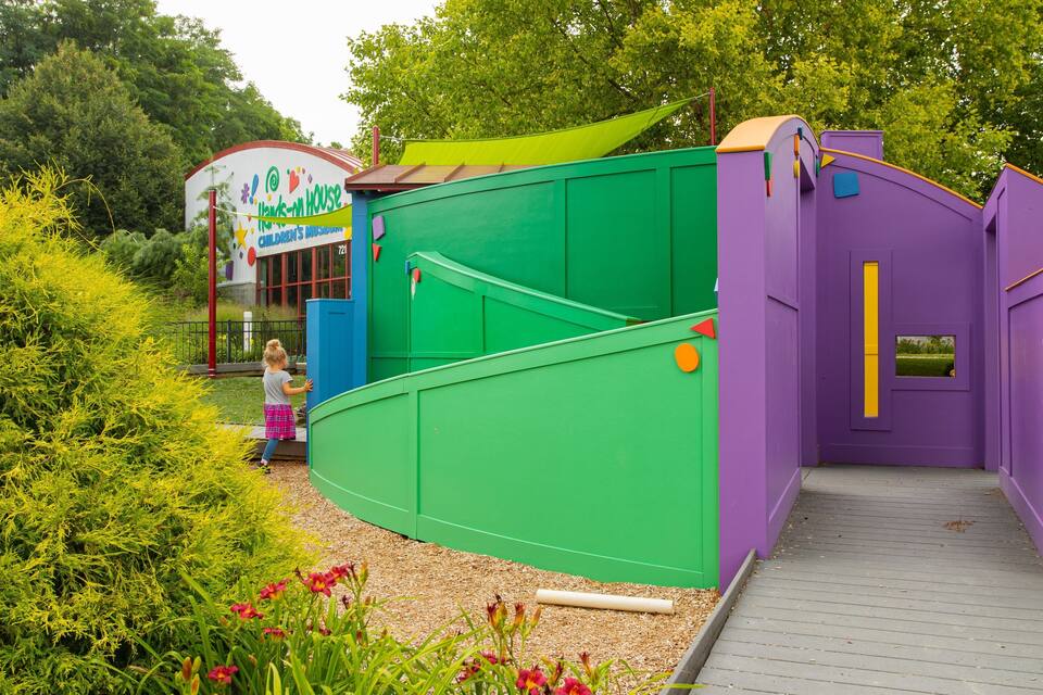 A children's museum with colorful buildings and a child approaching the entrance.