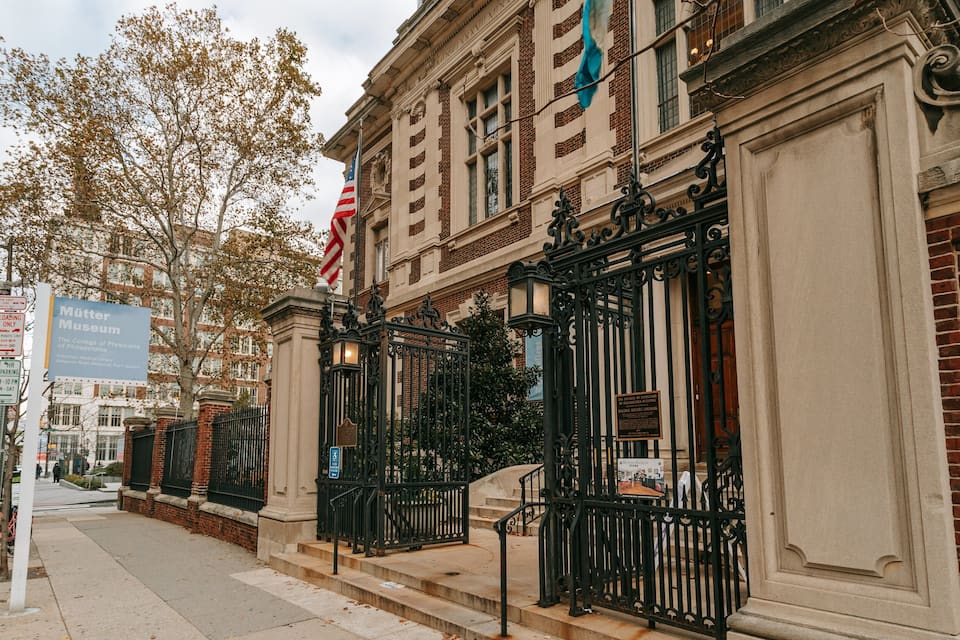 A historic building with a large American flag, a sign for the Mütter Museum, and a brick facade.