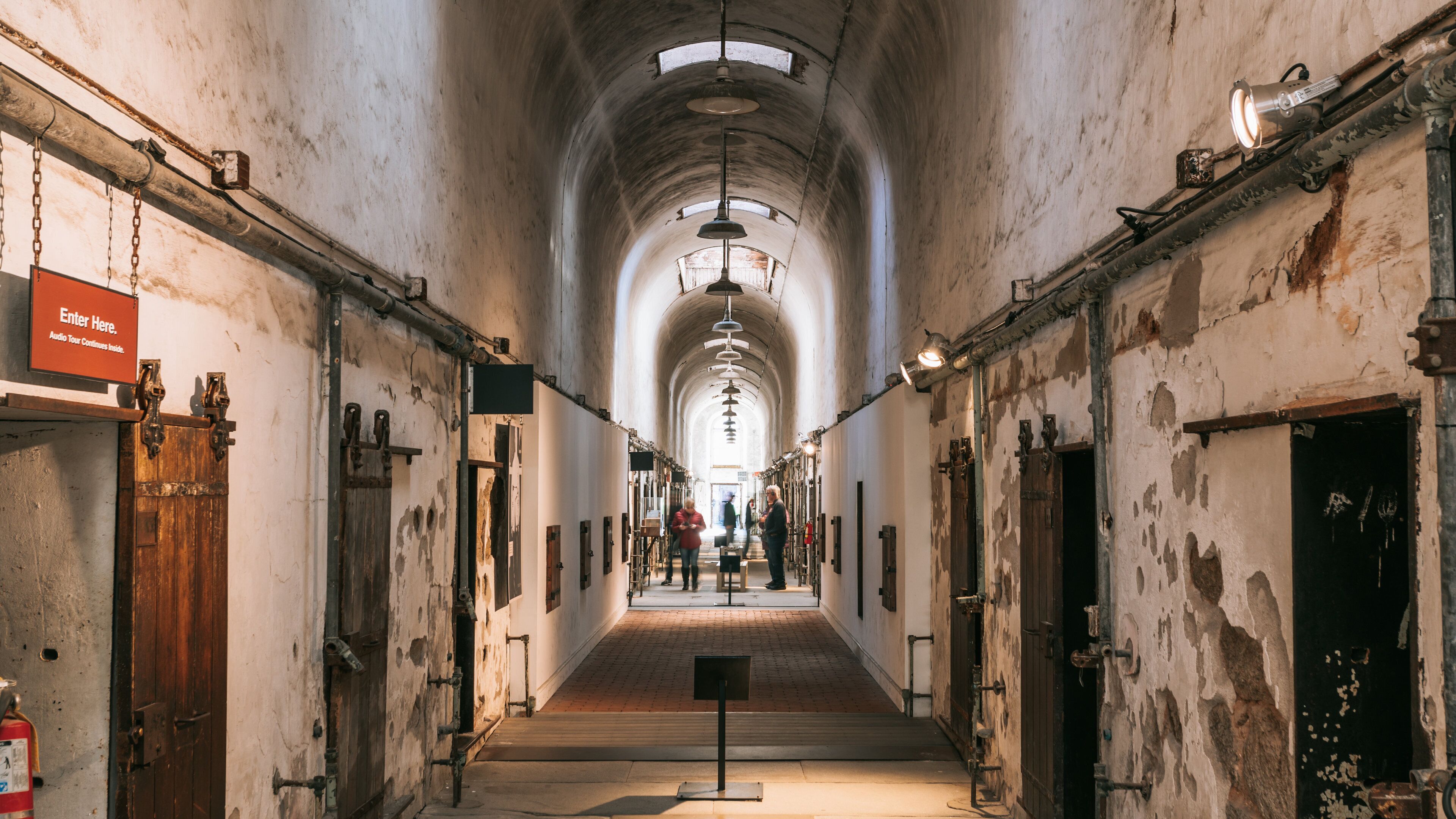 A long, arched corridor with wooden doors and metal fixtures.