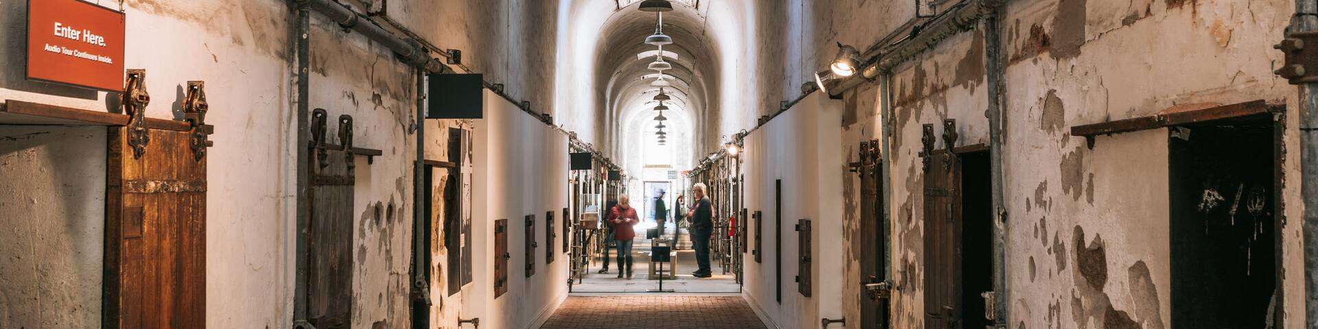 A long, arched corridor with wooden doors and metal fixtures.