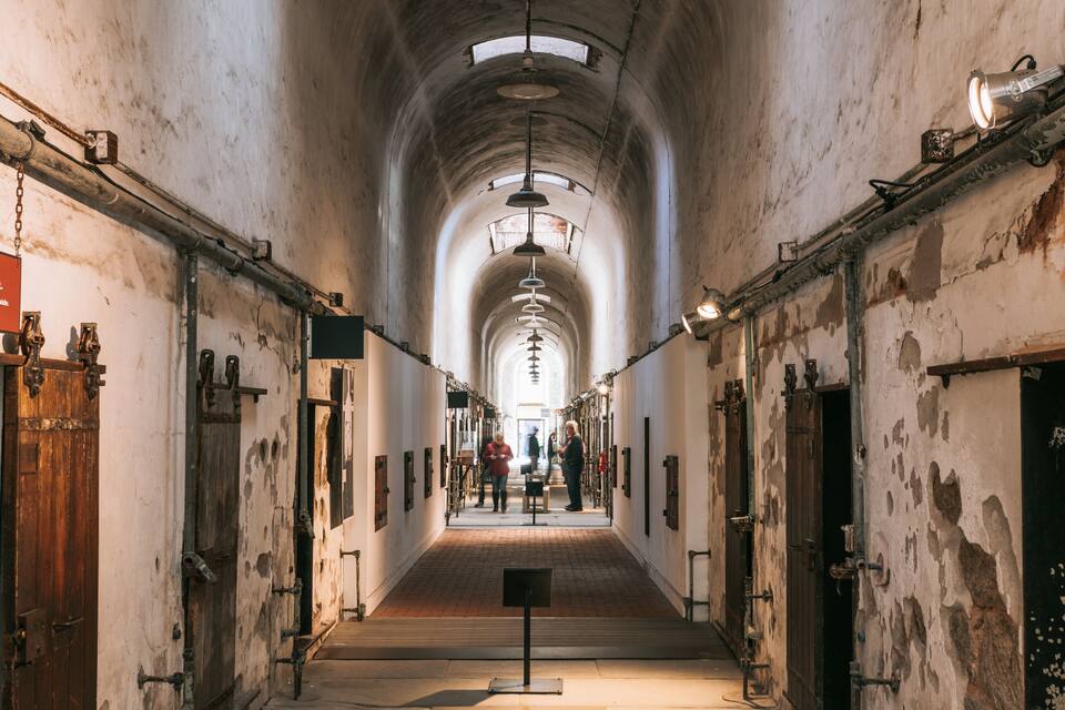 A long, arched corridor with wooden doors and metal fixtures.
