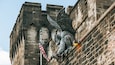 Une gargouille était perchée sur un mur de pierre, avec un drapeau américain devant.