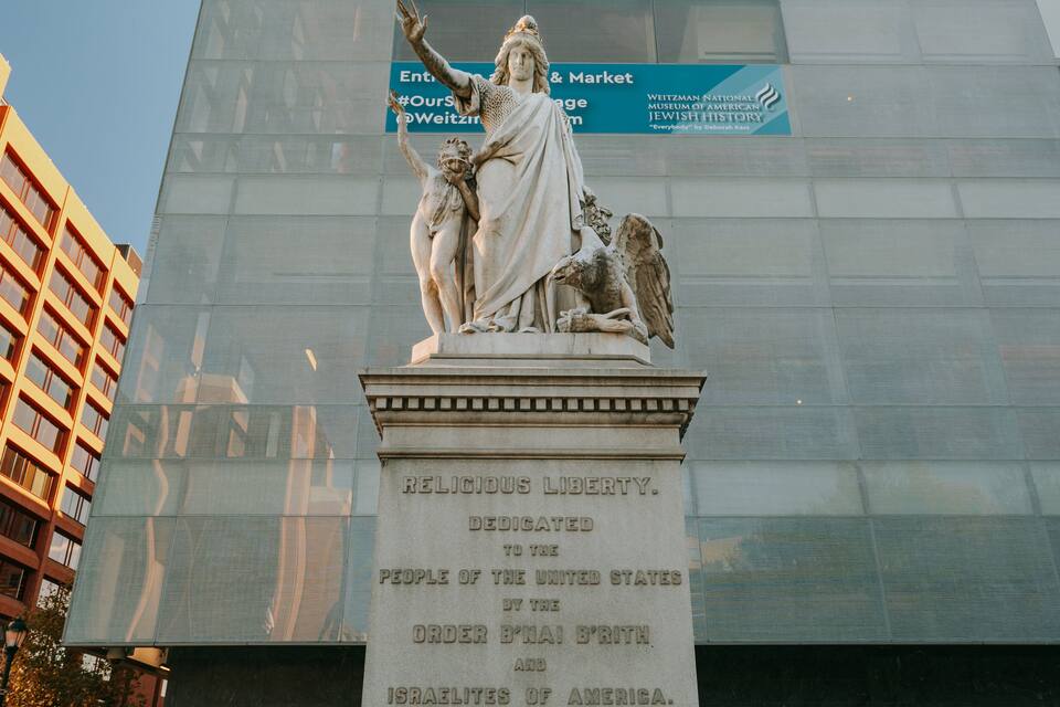 A statue of a woman holding a torch and a child, with a text plaque reading "Religious Liberty" dedicated to the people of the United States by the Order B'Nai B'rith and Israelites of America.