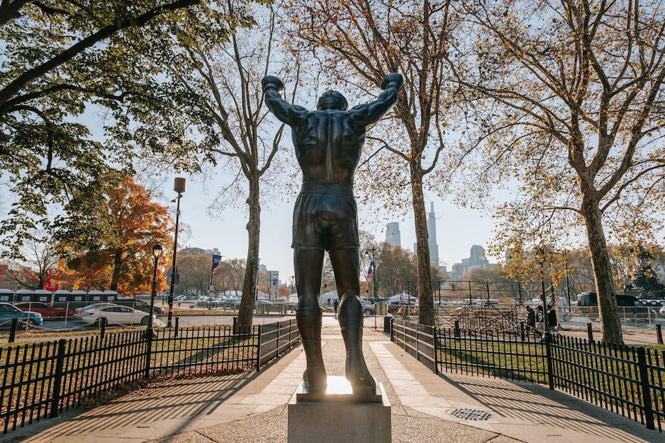 Estátua de um homem com os braços levantados em um parque.