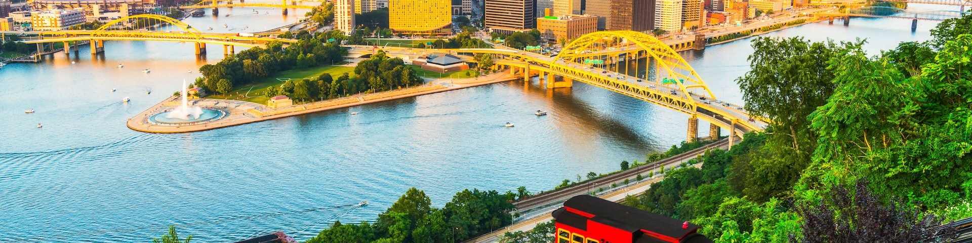 Eine Stadtlandschaft mit einer markanten, roten Standseilbahn, einem Fluss und einer gelben Brücke.