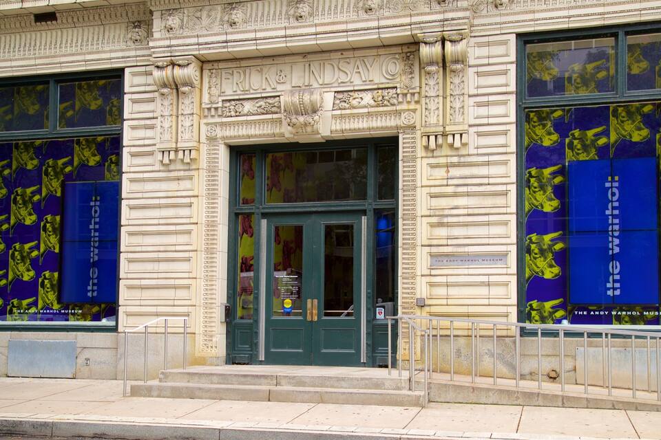 A building with ornate architectural details and large windows displaying artwork.