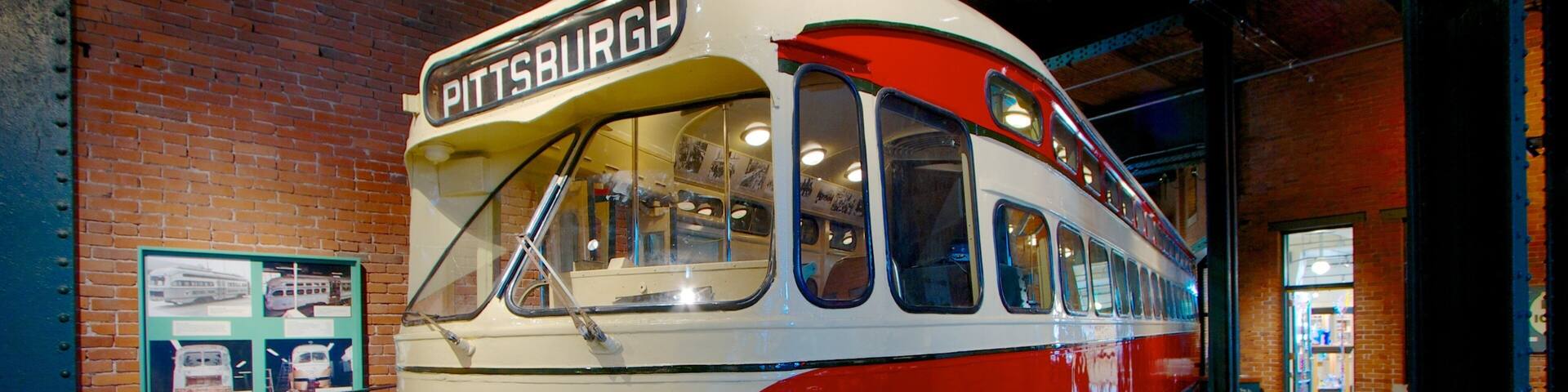 A vintage red and white bus with the number 1724, labeled 'Pittsburgh', displayed indoors.