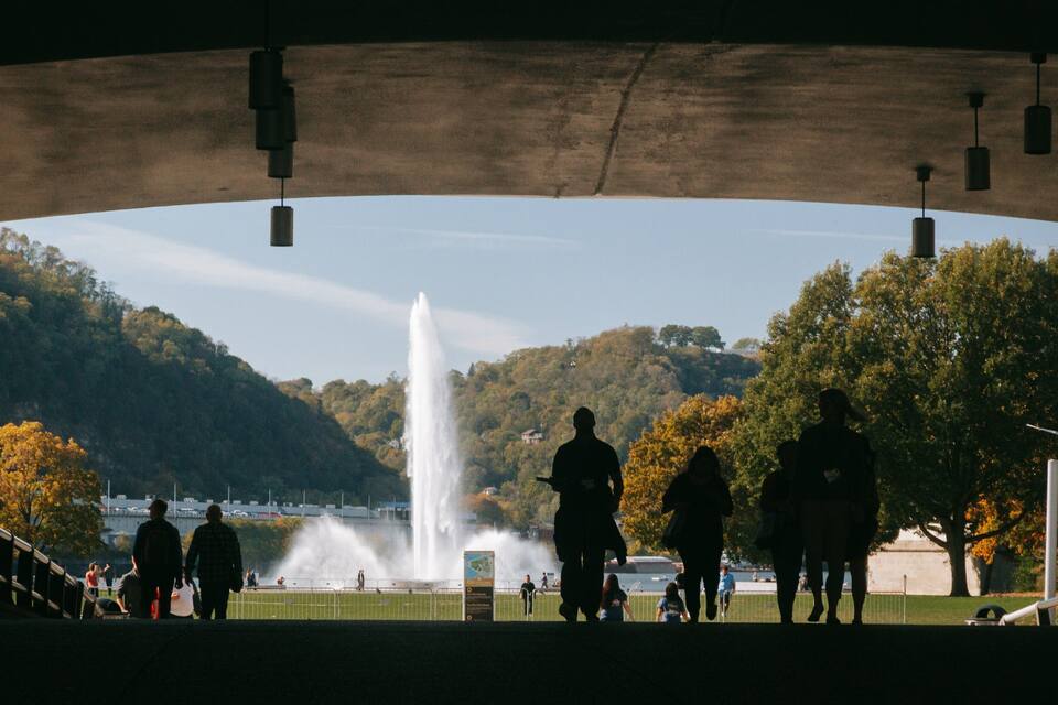 Een fontein in een park, mensen lopen in de buurt.