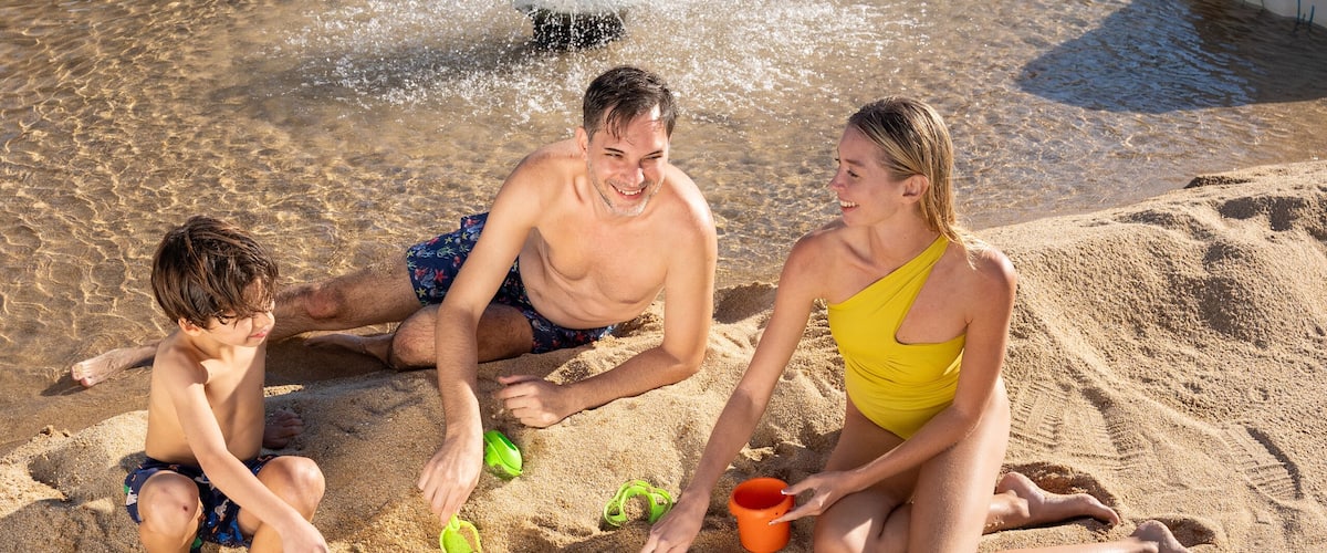 A happy family enjoying their time at a sand-themed aquapark, building sandcastles and playing together in a fun and lively atmosphere.