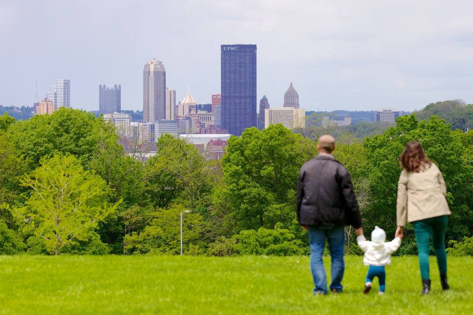 Une famille se promène dans un parc, avec la silhouette de la ville en arrière-plan.