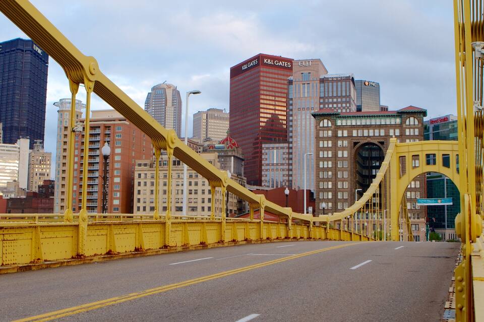 A yellow bridge with a city skyline in the background.