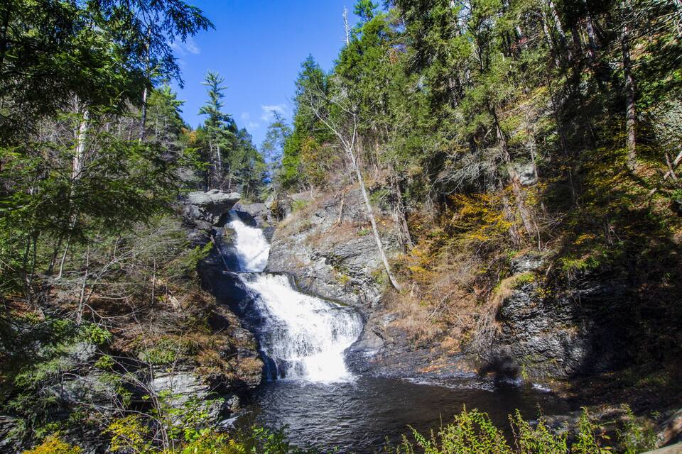 A waterfall surrounded by dense forest and rocky terrain.