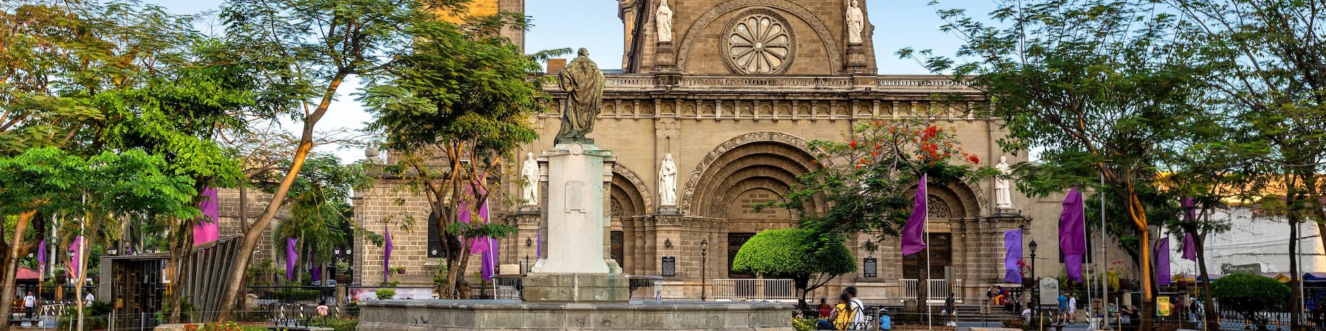A historic building with a clock tower and a statue in front.