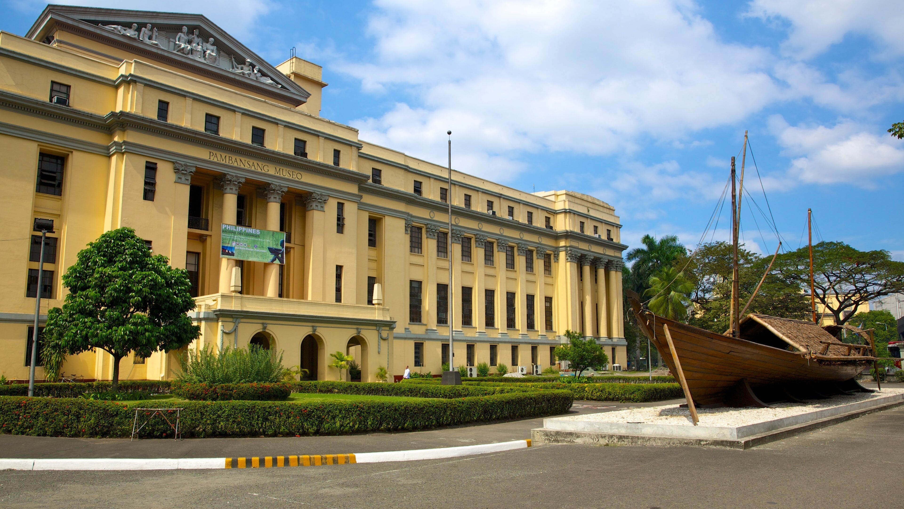 A large yellow building with columns and a sign that reads "Pambansang Museo".