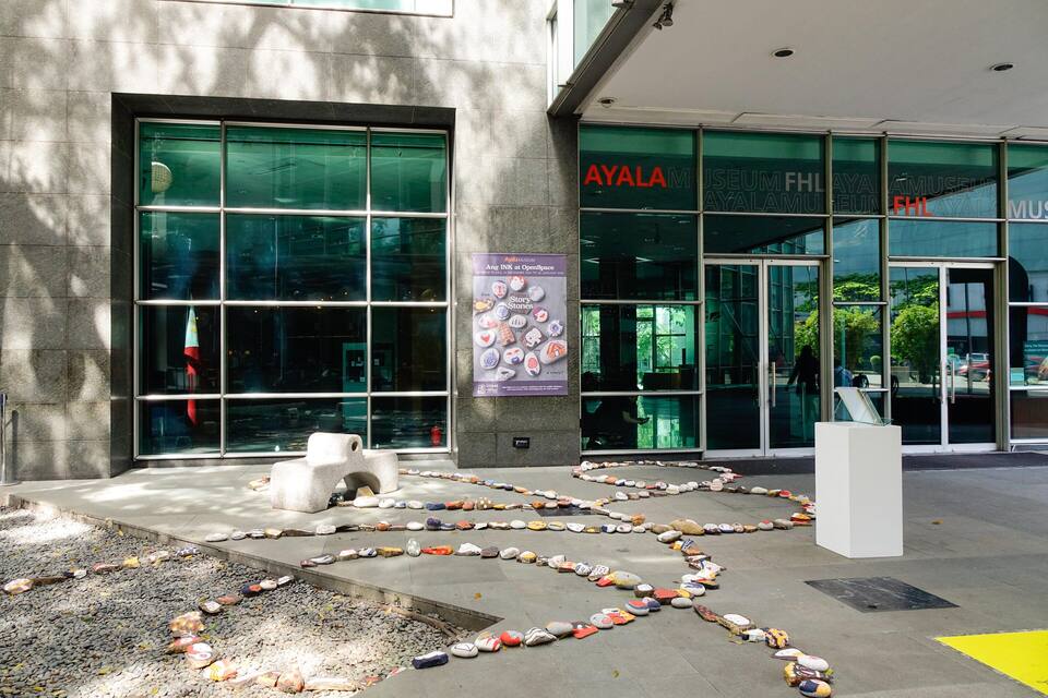 Um edifício moderno com grandes janelas de vidro e um caminho de pedras que leva à entrada.