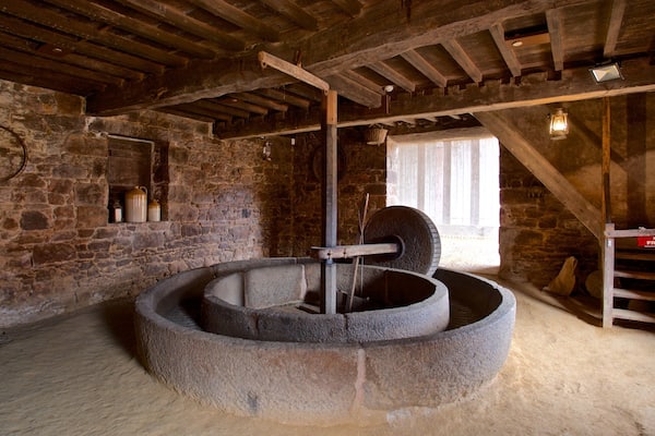 A stone mill with a wooden beam structure, stone walls, and a window.