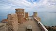 A stone fortification with a wooden walkway overlooking a calm sea.