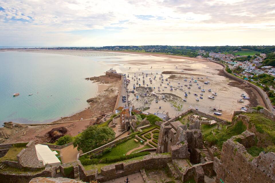 A coastal town with a historic fort, a sandy beach, and numerous boats anchored near the shore.