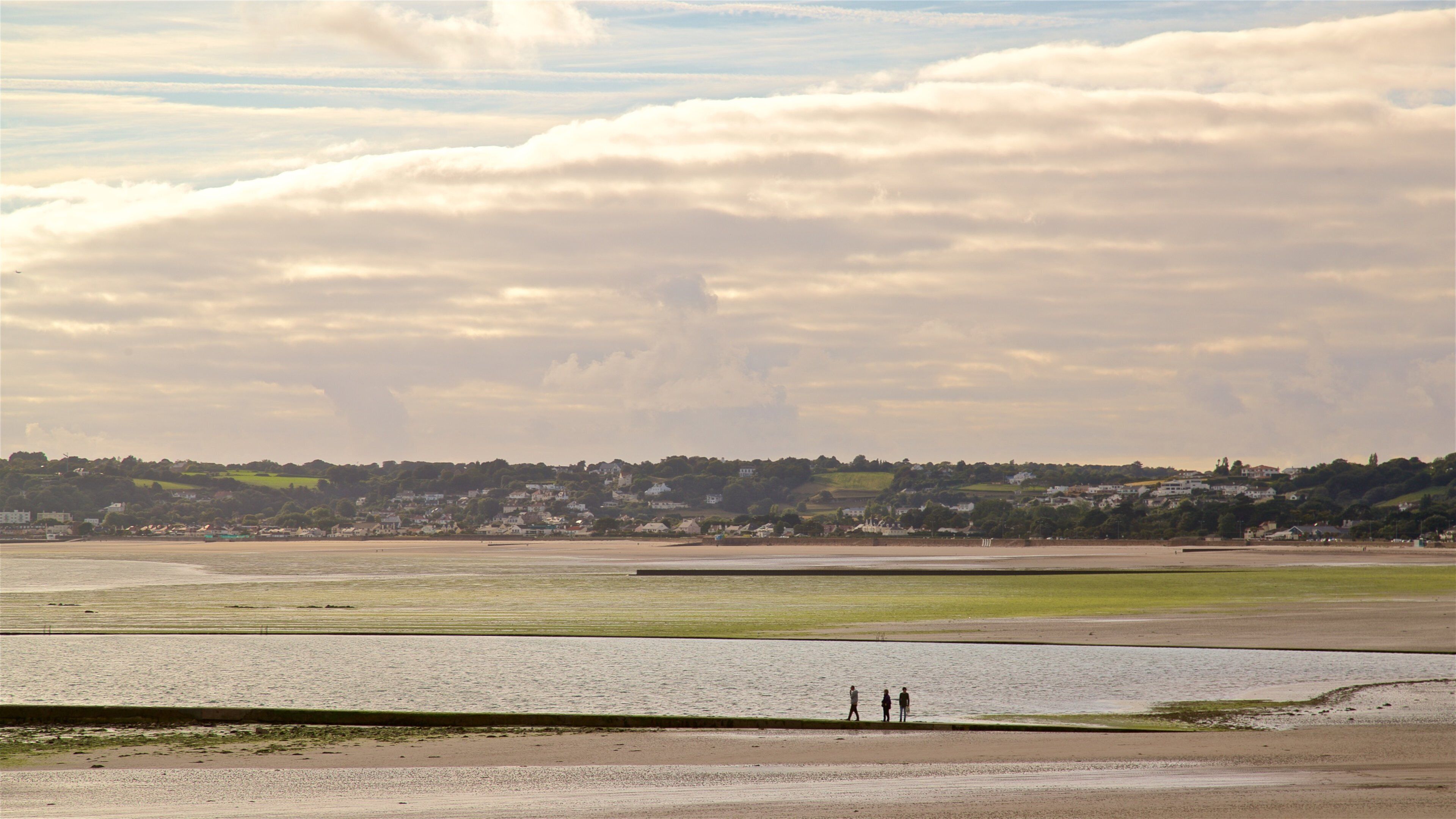 St. Helier Beach showing a sunset and landscape views as well as a small group of people