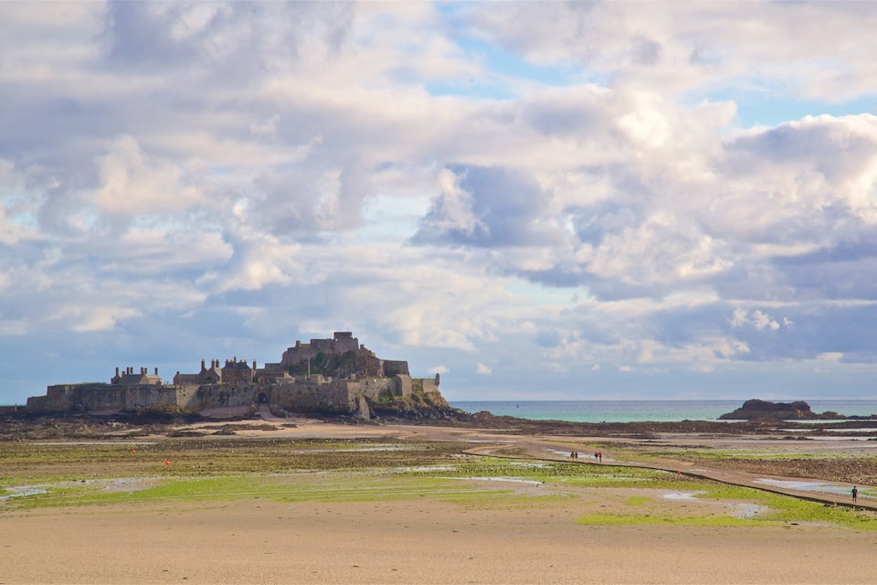 A coastal landscape with a historic fort on a cliff overlooking the sea.