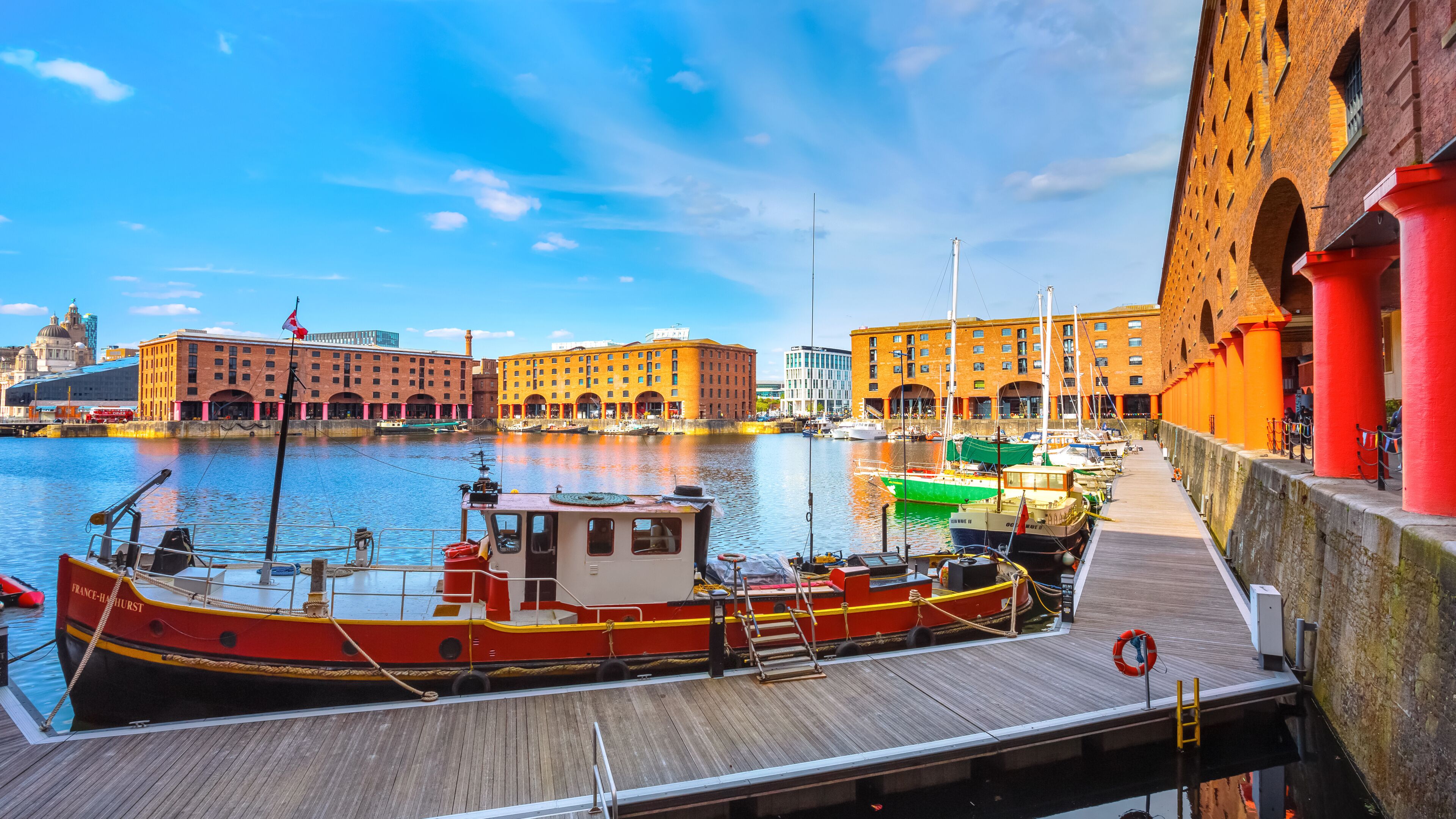 Un puerto con barcos amarrados, un edificio de ladrillo rojo y un cielo azul despejado.