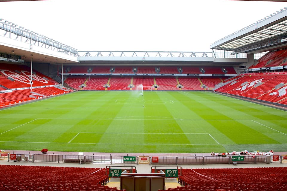 A large stadium with red seats and a green field.