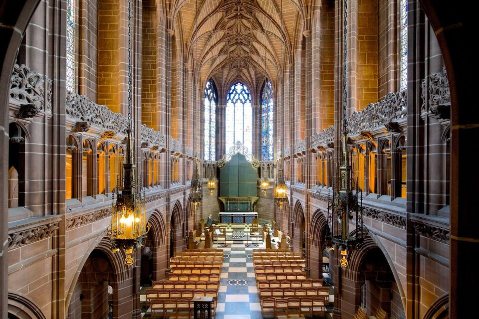 Interior d'una catedral amb alts sostres voltaics, finestres de vitralls i bancs de fusta ornamentals.