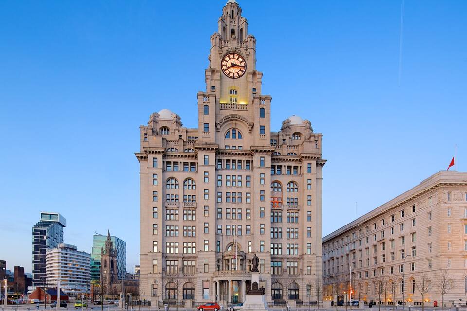 A historic building with a clock tower, surrounded by modern skyscrapers.