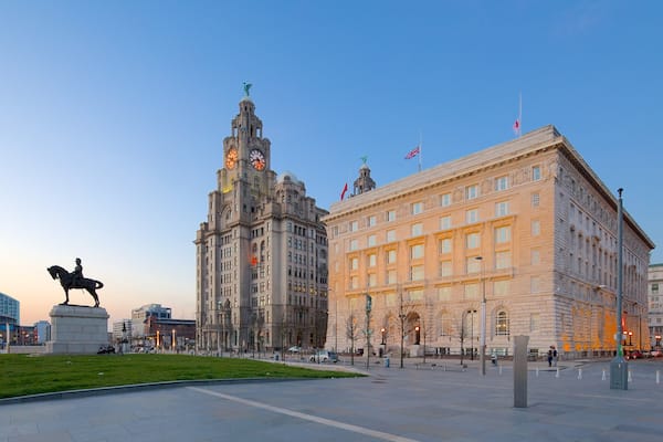 Une place de ville avec une statue, un beffroi et des bâtiments historiques.