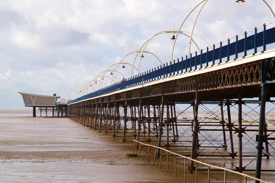 A long pier with a series of arches and a covered seating area at the end.