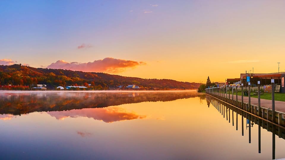 A bridge over a calm lake with autumn foliage on the hills.