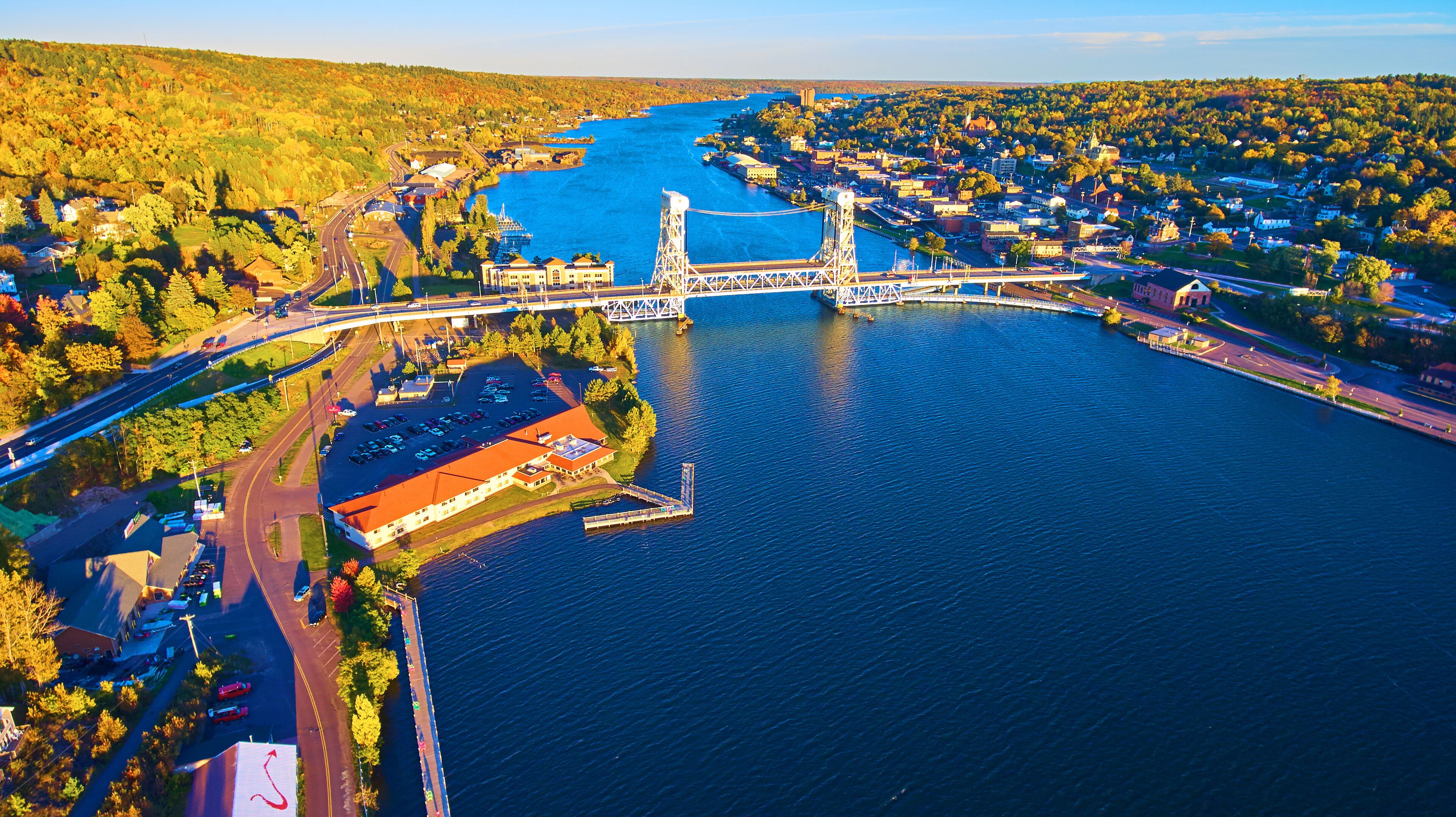 A river with a bridge, a town on the opposite bank, and surrounding hills.