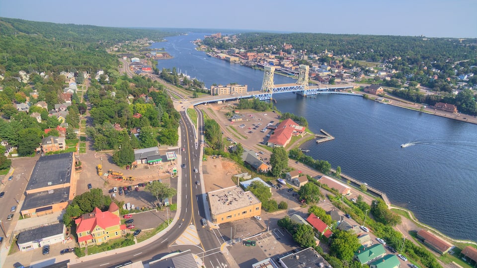 An aerial view of a city with a river, a bridge, and surrounding greenery.