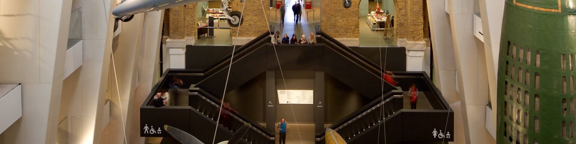 A fighter jet suspended in a museum with a brick wall and stairs in the background.