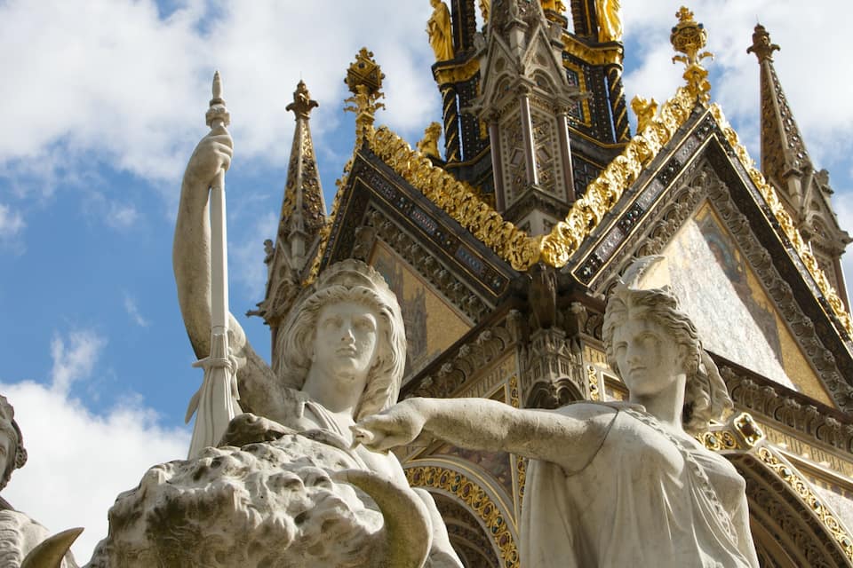 A statue of a woman holding a torch, with a golden roof and intricate architectural details in the background.