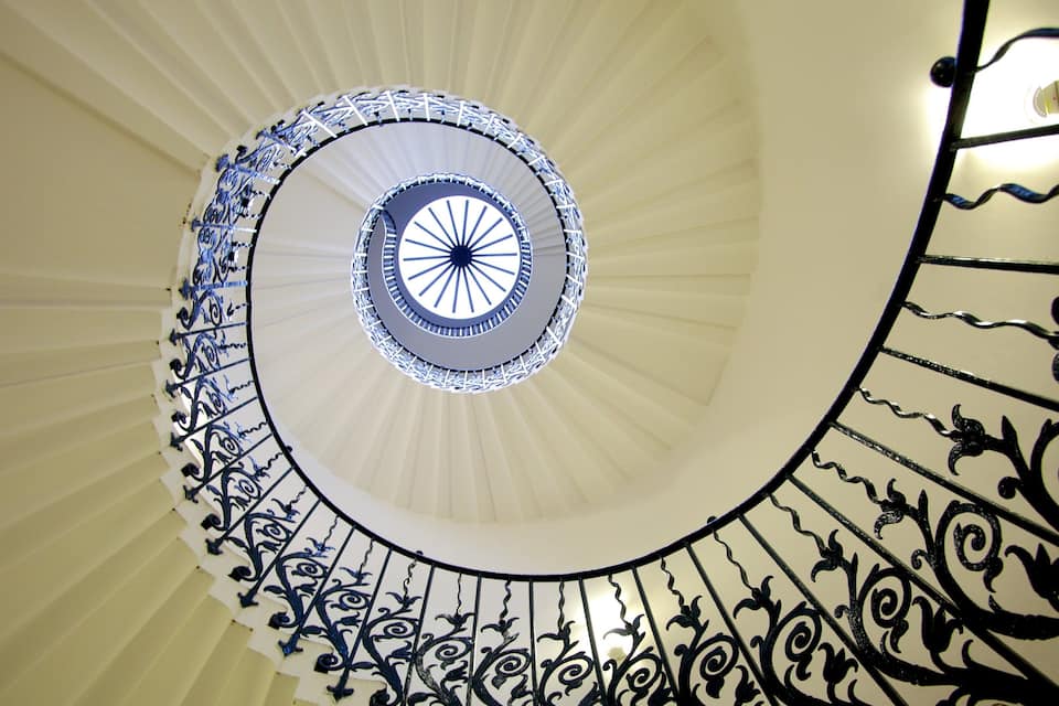 A spiral staircase with ornate black railings and a white interior.