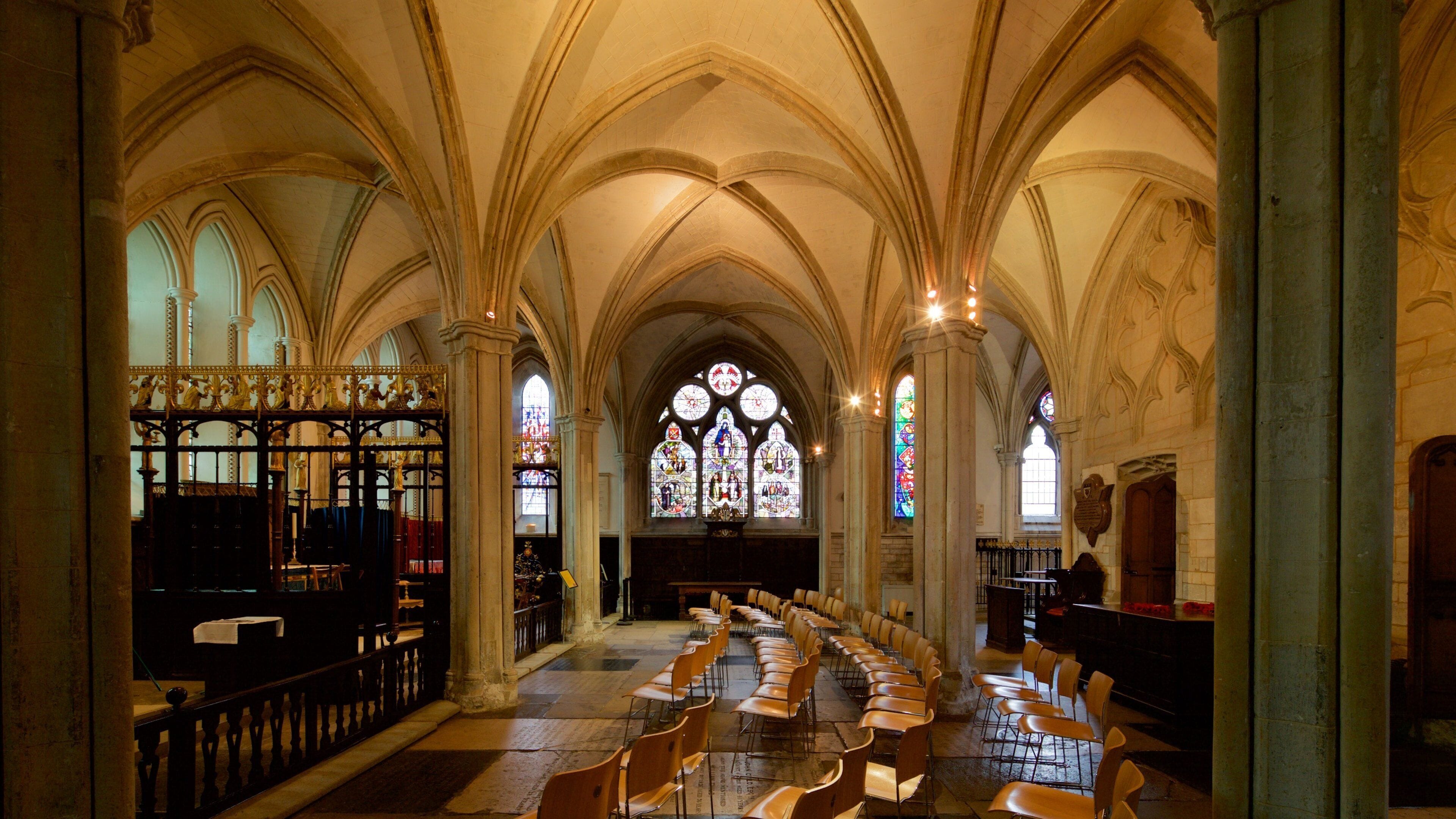 A church interior with arched ceilings, stained glass windows, and rows of chairs.