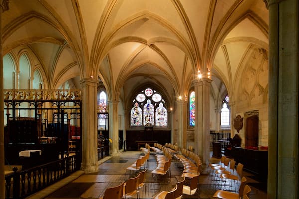 L’intérieur d’une église, avec des voûtes en arc, des vitraux et des rangées de chaises.