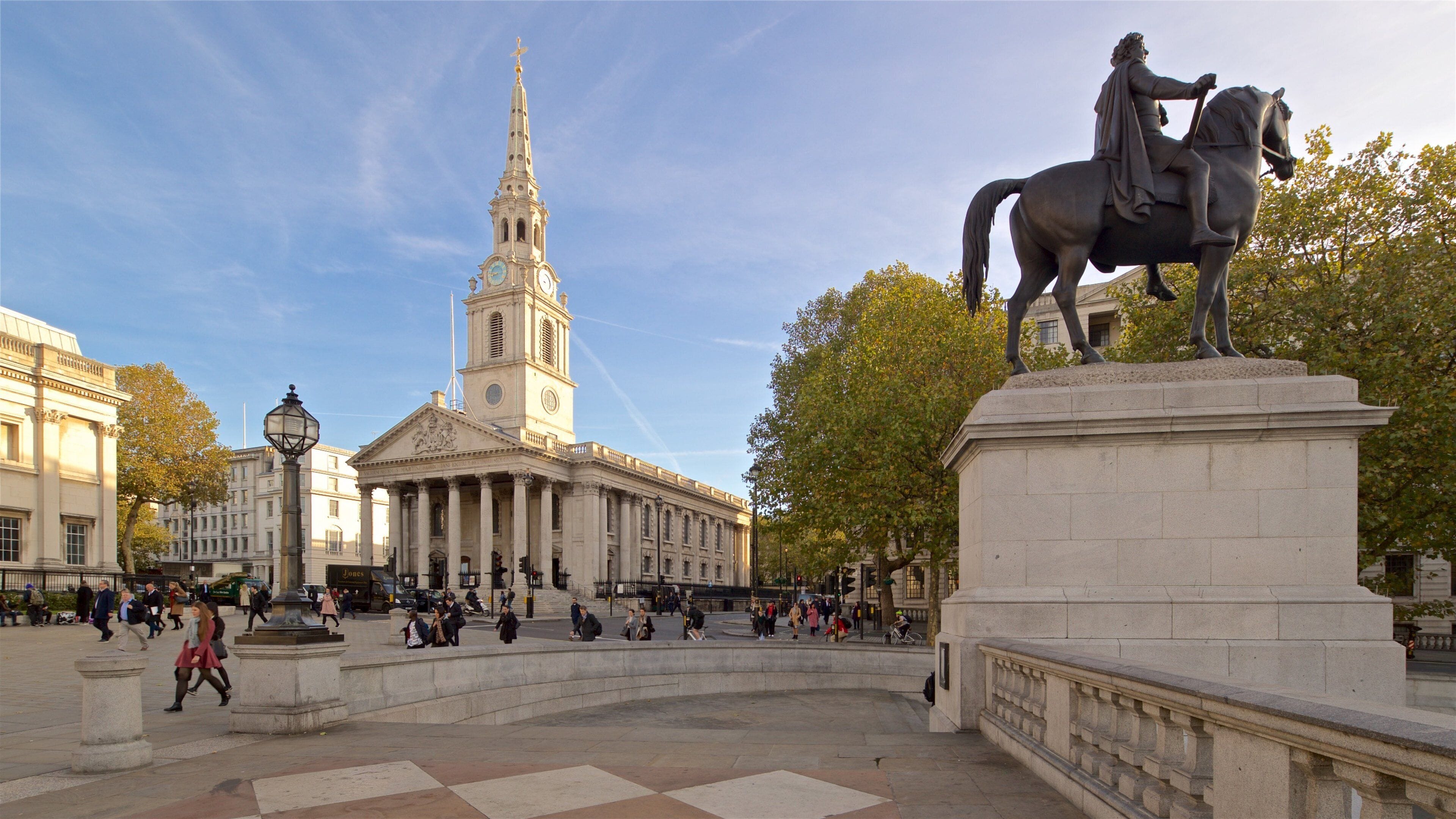 A statue of a man on horseback, a large building with columns, and a clock tower.