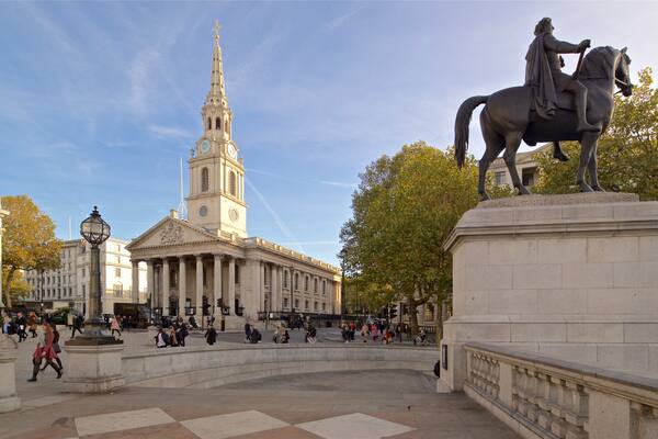 A statue of a man on horseback, a large building with columns, and a clock tower.