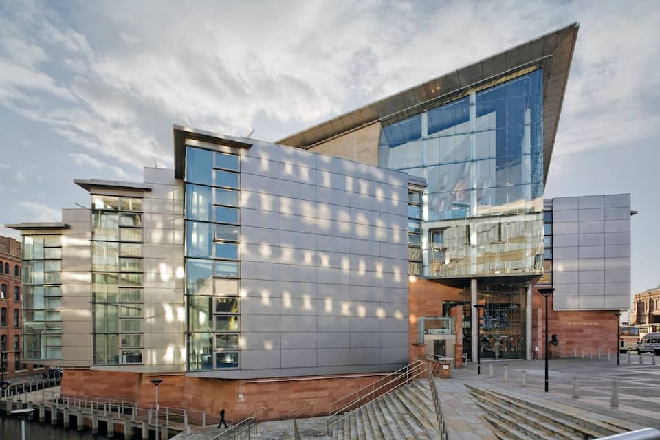 A modern building with large glass windows and a sloped roof.
