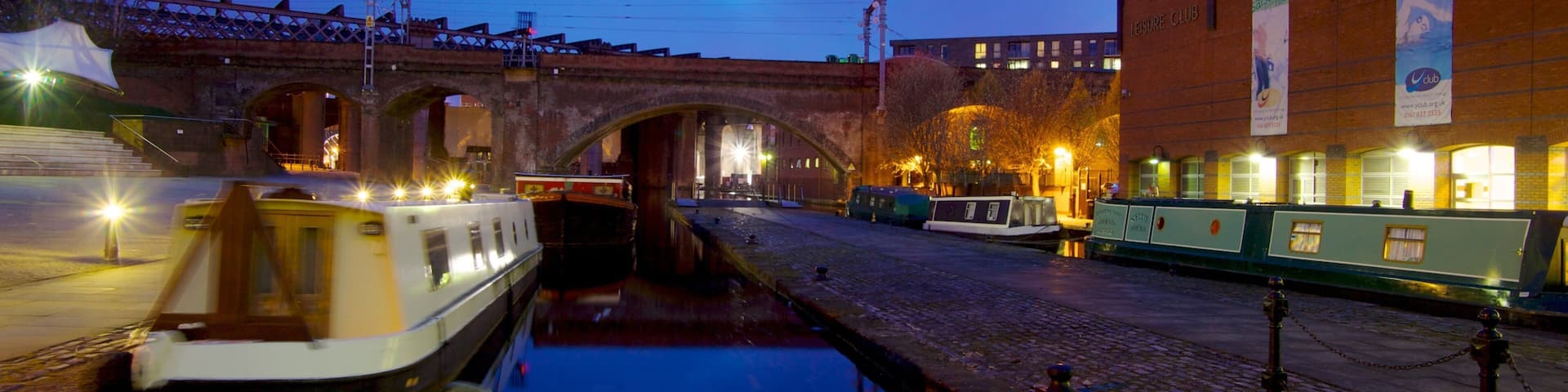 A canal with boats, a bridge, and a building with a sign.