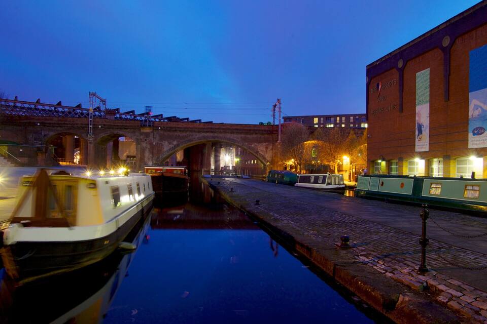 A canal with boats, a bridge, and a building with a sign.