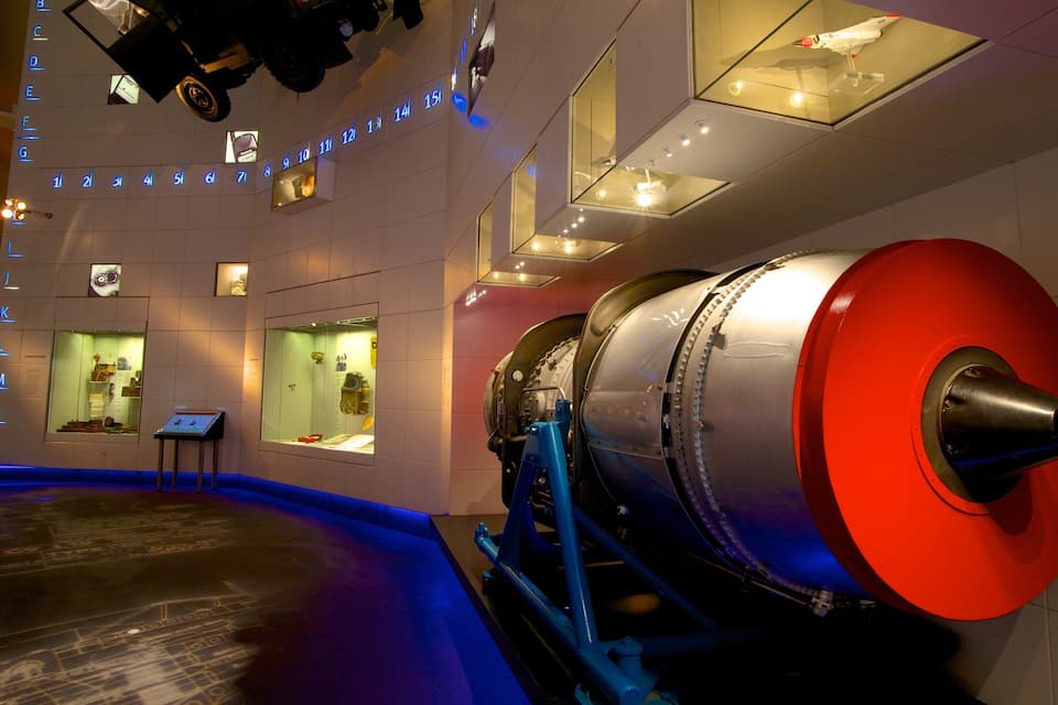Une exposition de musée comprenant un grand modèle de moteur, des panneaux d’information et une vitrine.