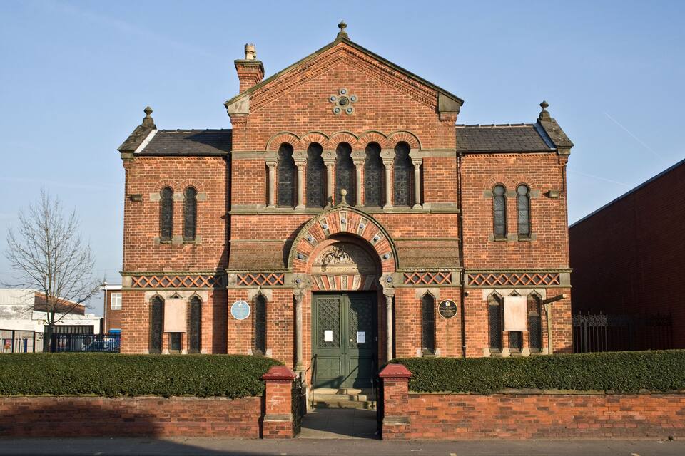 A historic brick building with a prominent arched entrance and decorative brickwork.