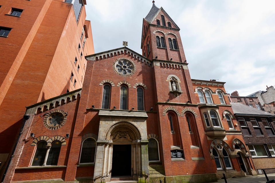 A large red brick church with a tall tower and arched windows.
