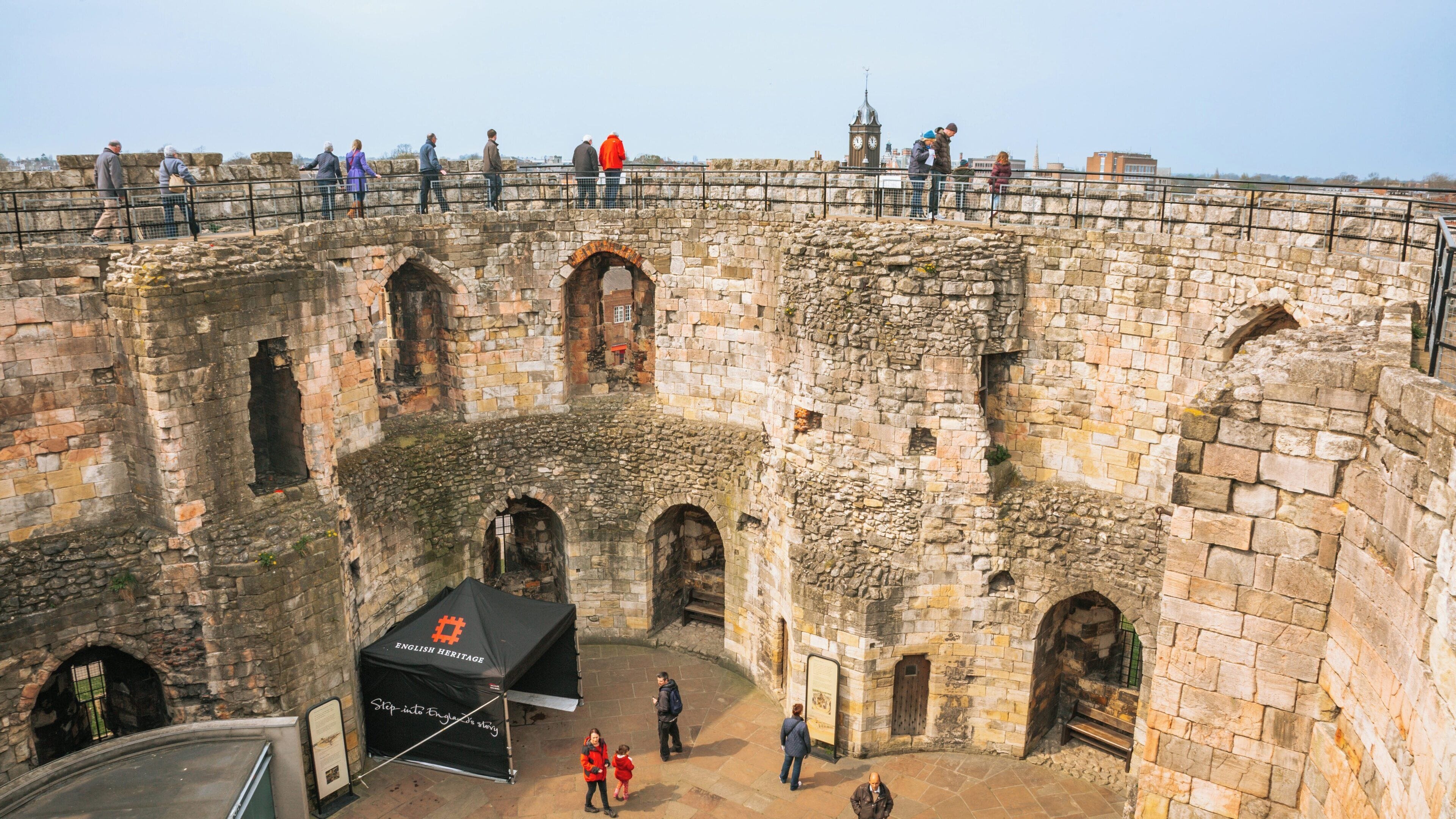 Visitors explore the historic Clifford's Tower in York, England, surrounded by stunning medieval architecture and panoramic views