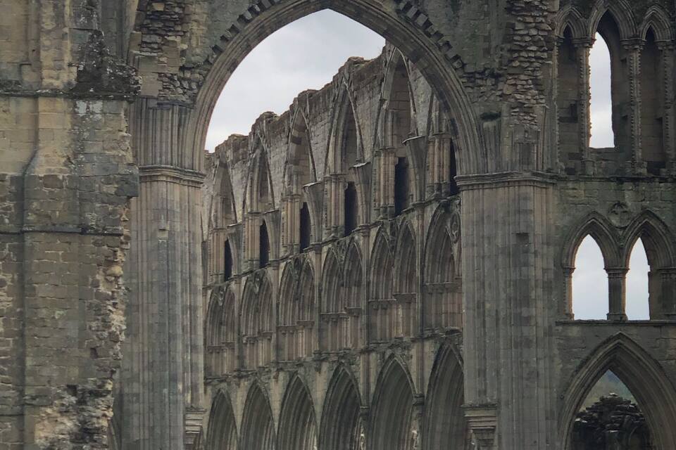 The ruins of a large Gothic cathedral with multiple arches and columns.